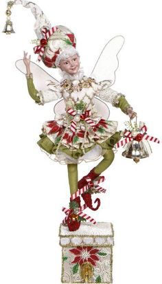 a christmas fairy figurine on top of a box with candy canes and bells