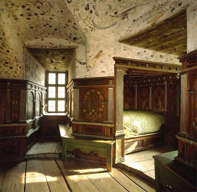 an old fashioned bedroom with wooden floors and carved woodwork on the walls, along with large windows