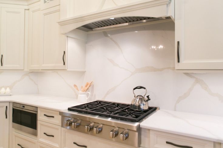 a stove top oven sitting inside of a kitchen next to white cupboards and counter tops