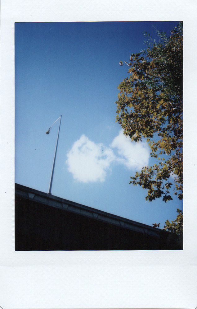 an old photo of a flag pole and clouds in the sky over a roof top