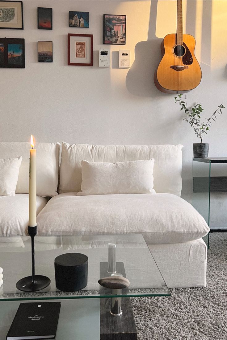 a living room with a couch, table and guitar hanging on the wall above it