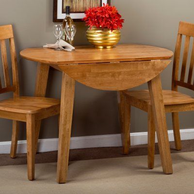 a wooden table with two chairs next to it and a vase filled with red flowers