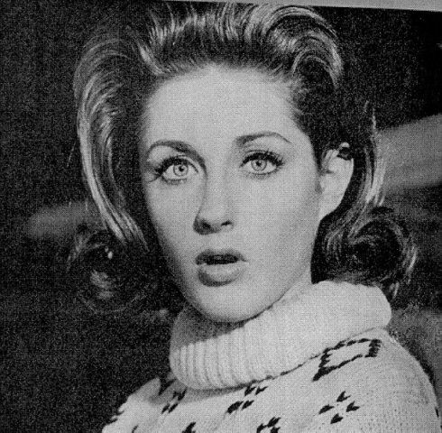 an old black and white photo of a woman wearing a sweater with her eyes open