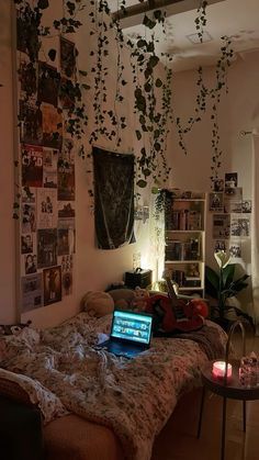 a laptop computer sitting on top of a bed in a room filled with pictures and plants