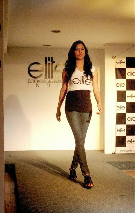 a woman is walking down the runway in tight jeans and heels with an embellishment on her t - shirt