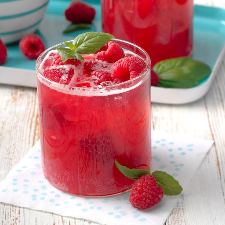 two glasses filled with raspberry lemonade and mint garnish on a table