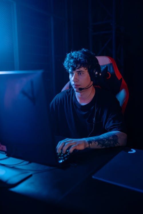 a man sitting in front of a computer with headphones on and his hands resting on the keyboard