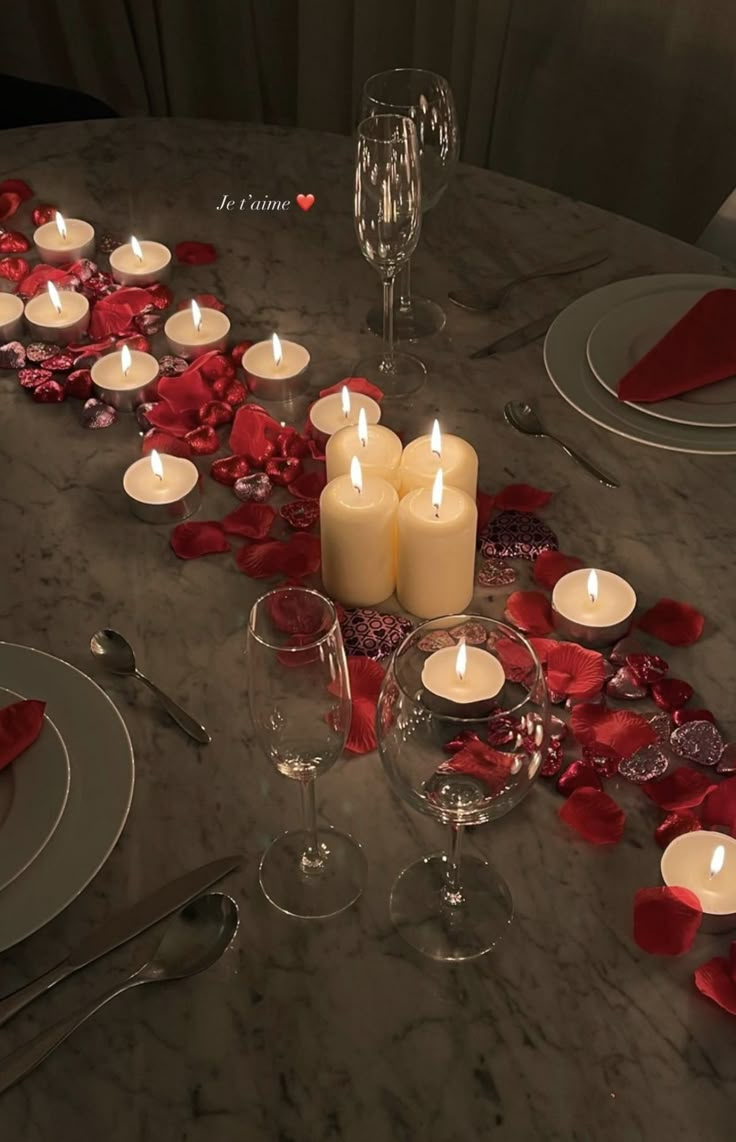 the table is set with candles and rose petals on it for a valentine's day dinner