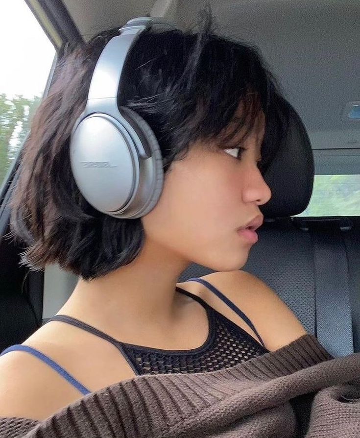 a woman wearing headphones sitting in the back seat of a car