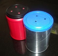 two plastic trash cans sitting on top of a table next to each other, one red and one blue