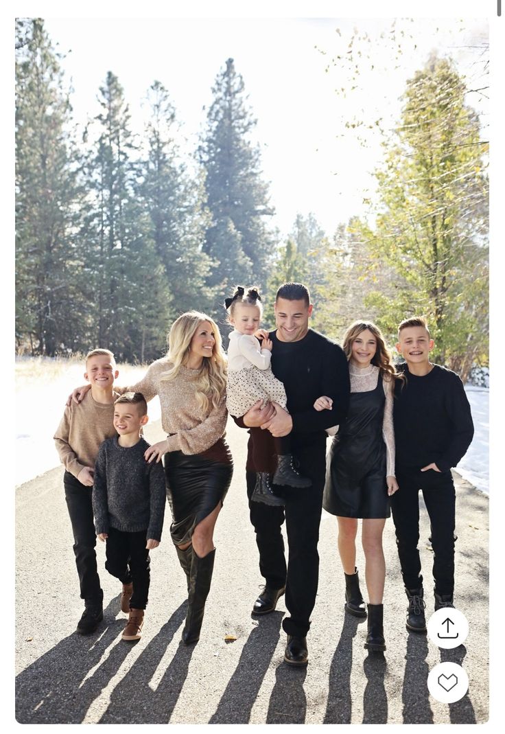 a family is posing for a photo in the park with their two children and one adult