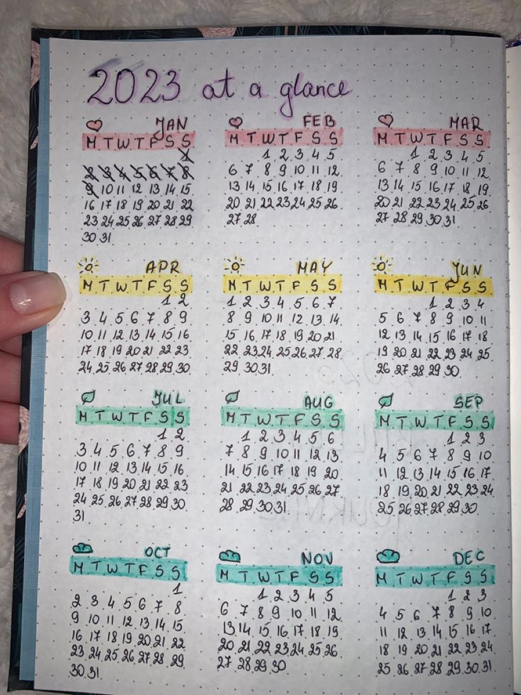 a hand holding a planner with the dates on it and numbers in different colors,