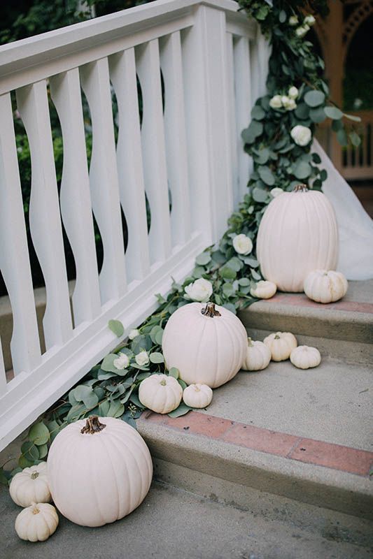 some white pumpkins are sitting on the steps