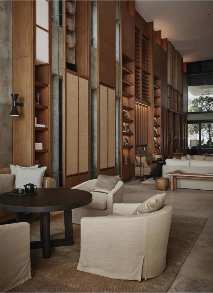 a living room filled with lots of furniture and bookshelves next to a window