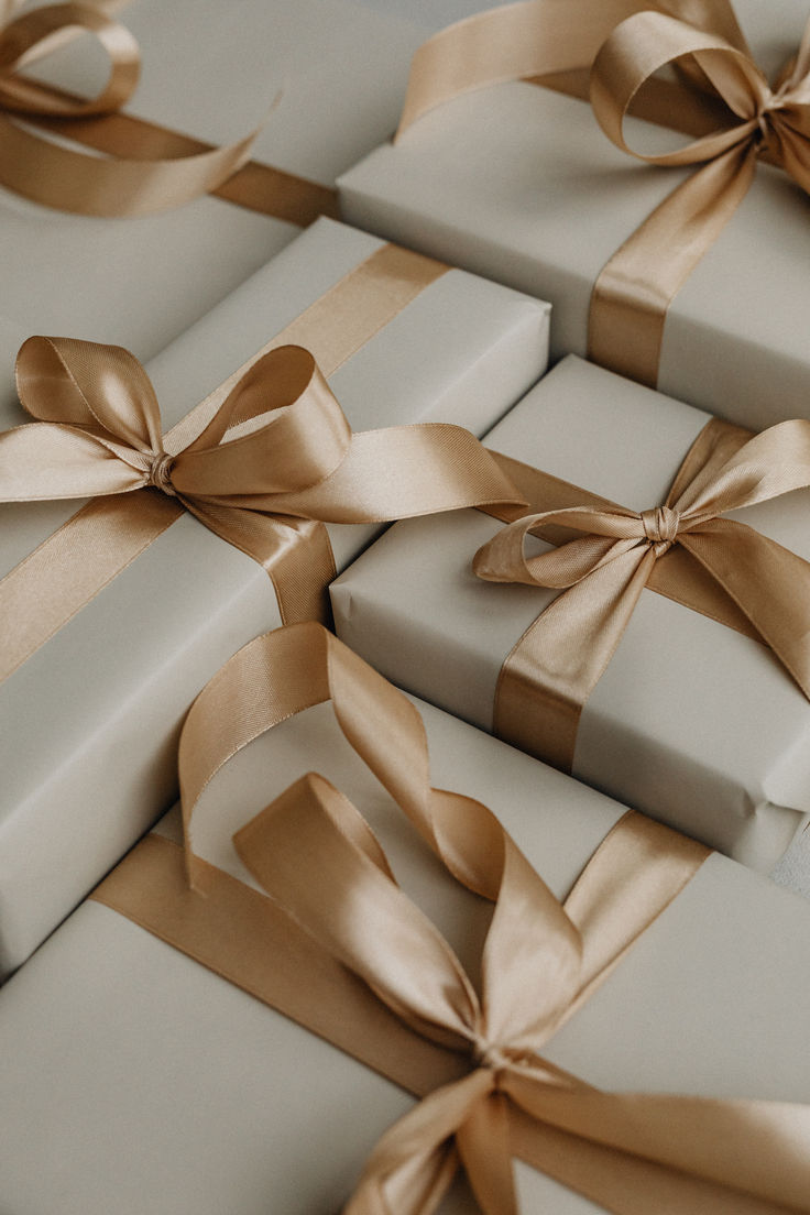 many wrapped presents with gold ribbons and bows