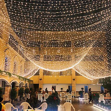 the inside of a building with tables and chairs covered in fairy lights on the ceiling