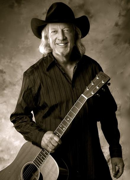 a man in a cowboy hat holding a guitar and posing for a photo with his name on it