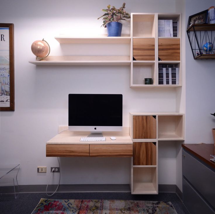 a desk with a computer monitor and keyboard on it in front of a book shelf