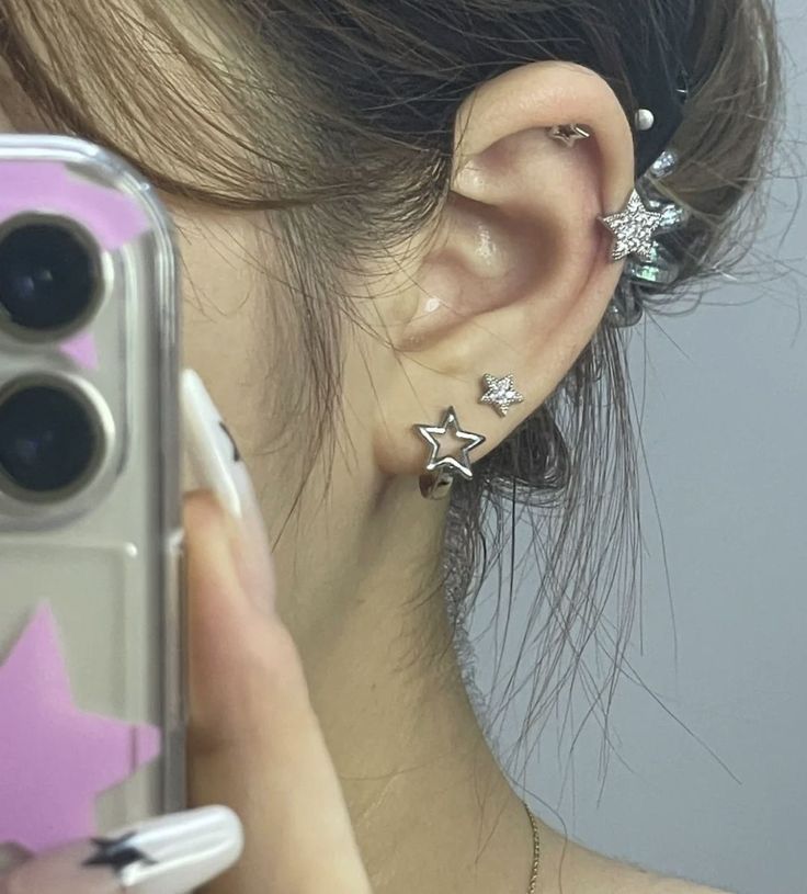 a woman with ear piercings taking a selfie in front of her cell phone