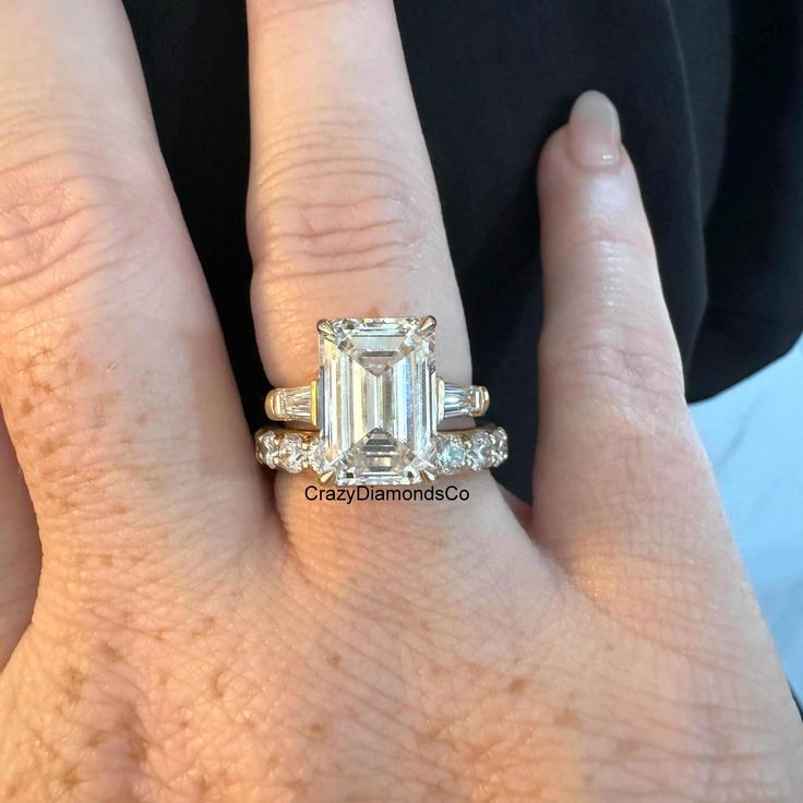 a woman's hand with an emerald and diamond engagement ring on her left hand