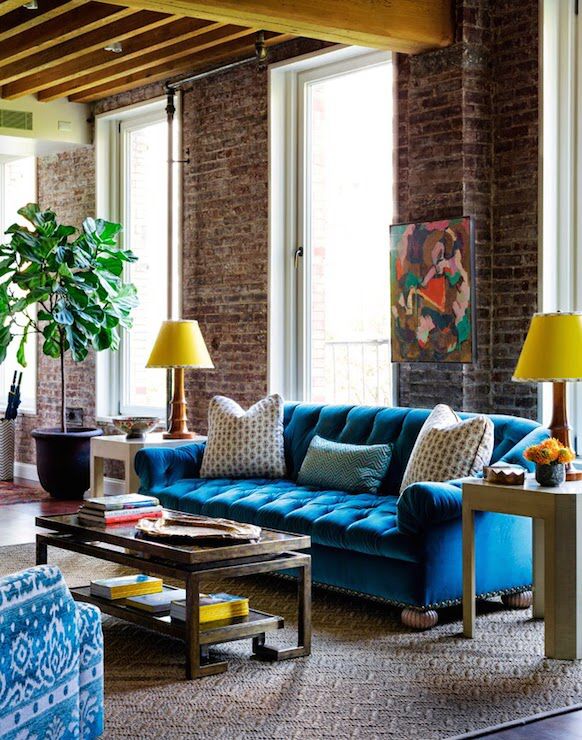 a living room with blue couches and yellow lamps on the table in front of it