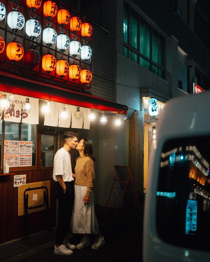 two people standing in front of a building at night