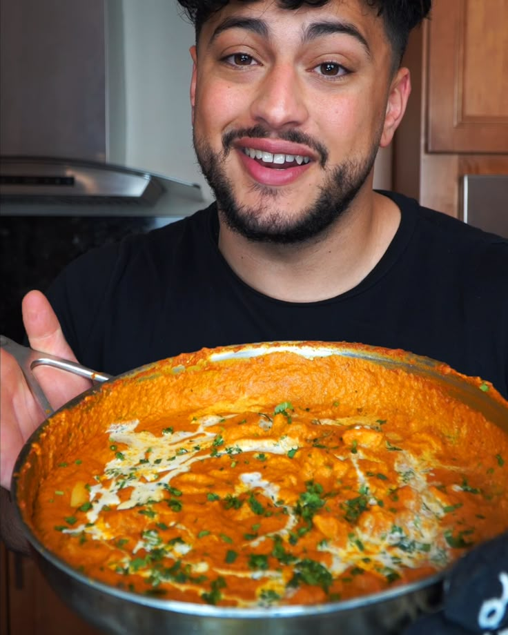 a man is holding a large bowl of soup in his hands and smiling at the camera