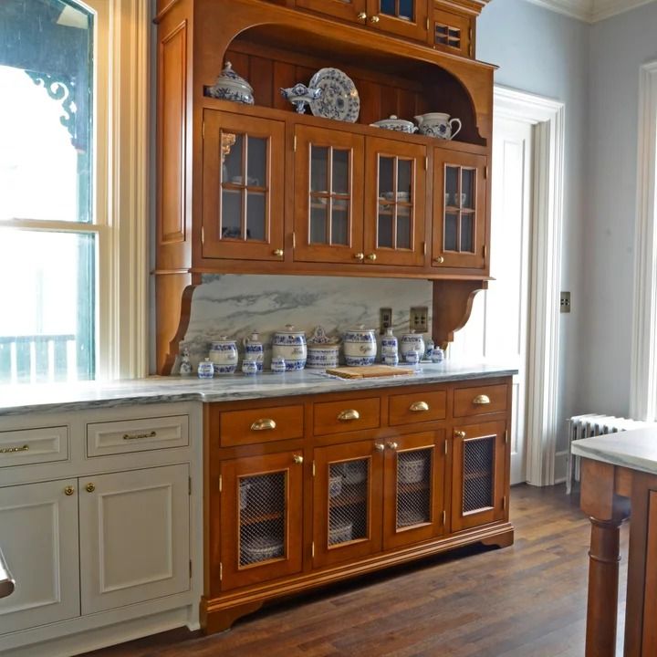 a kitchen with wooden cabinets and marble counter tops, along with hardwood flooring that matches the walls