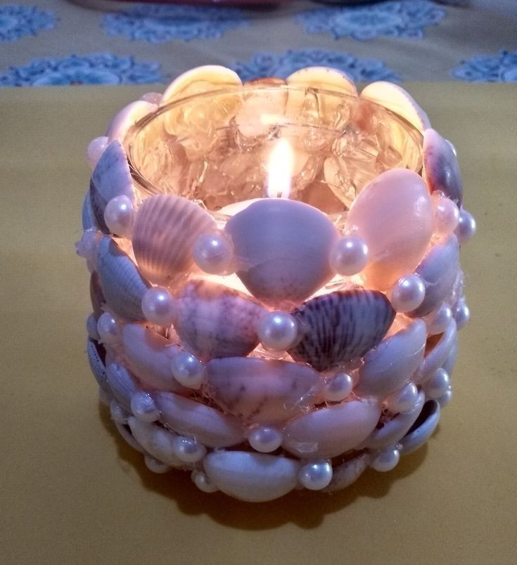 a candle that is sitting on a table next to some seashells and pearls