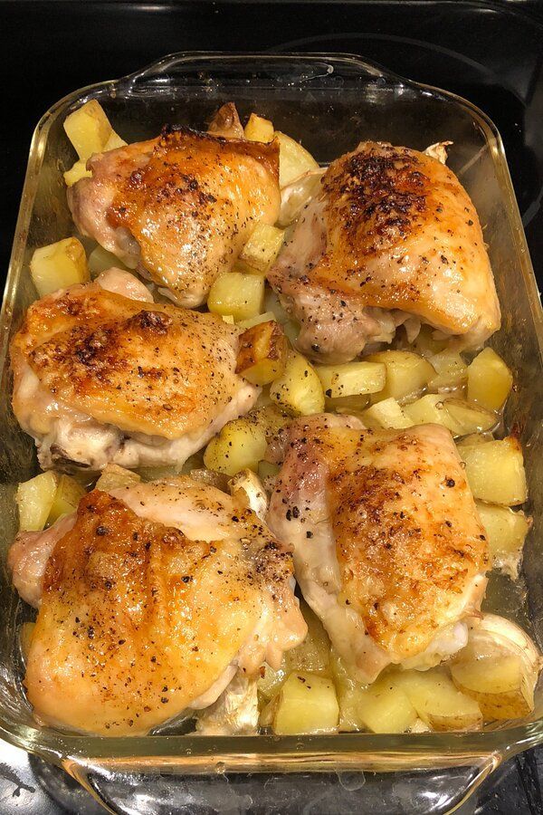 chicken and potatoes in a baking dish on the stove top, ready to be cooked