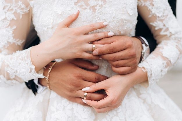 the bride and groom are holding each other's hands while they hold their wedding rings