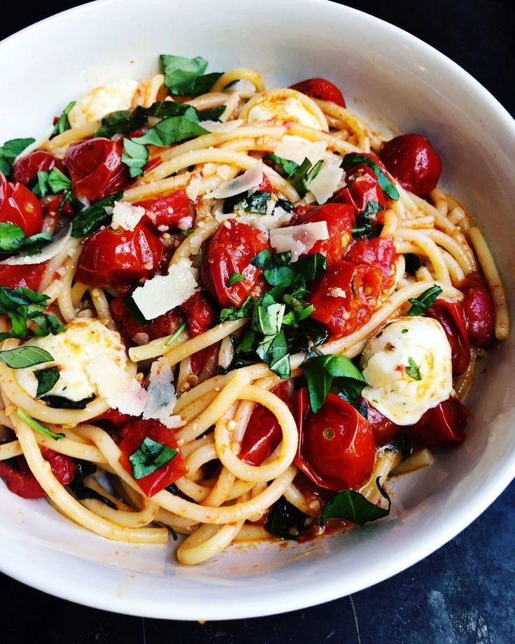 a white bowl filled with pasta and tomatoes