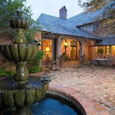 a large brick house with a fountain in the front yard and patio area at night