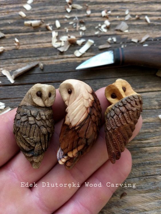 three small owls sitting on top of each other in someone's hand next to a knife