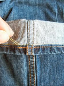 someone is sewing on the back pocket of their jeans