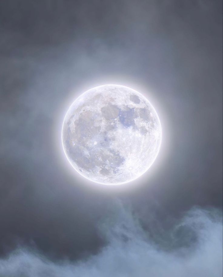 the full moon is seen through dark clouds