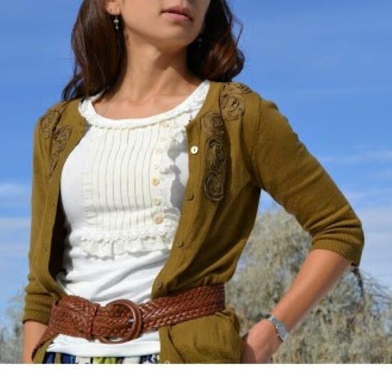 a woman standing with her hands on her hips wearing a brown cardigan and white top