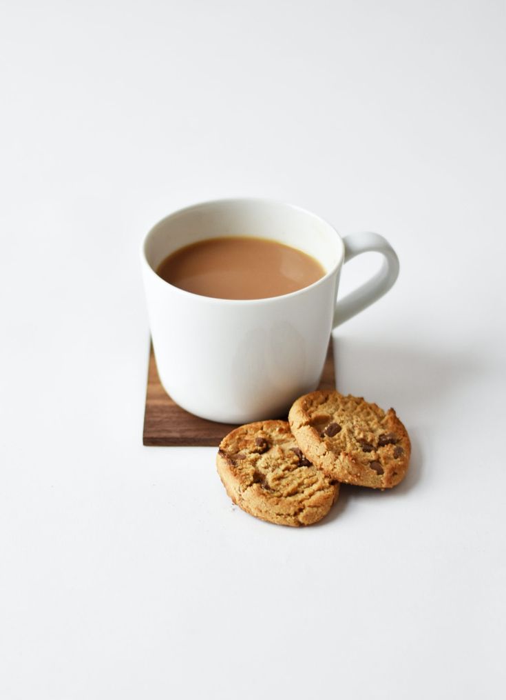 a cup of coffee and two cookies on a coaster