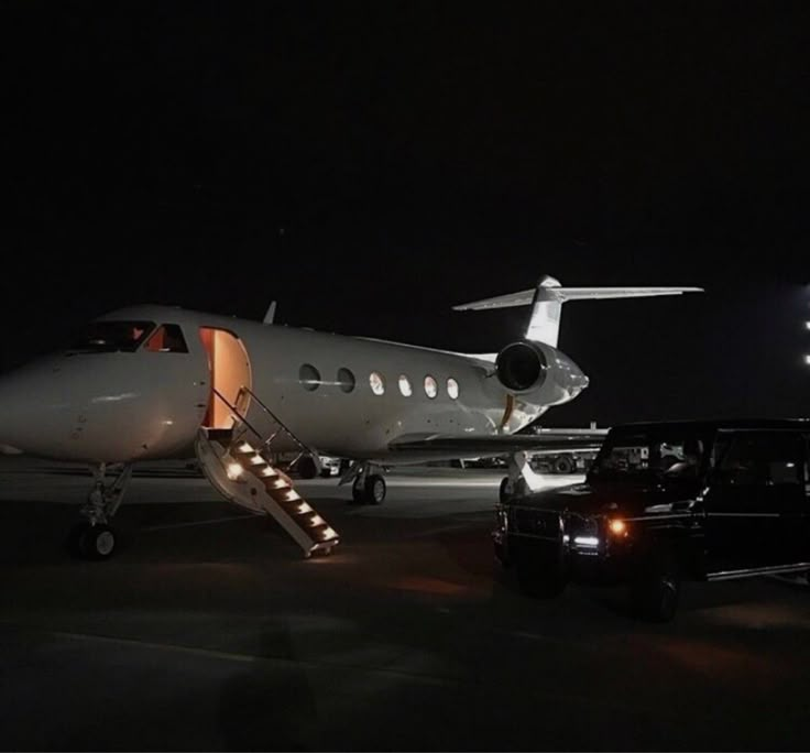 an airplane is parked on the tarmac at night with its door open and lights on