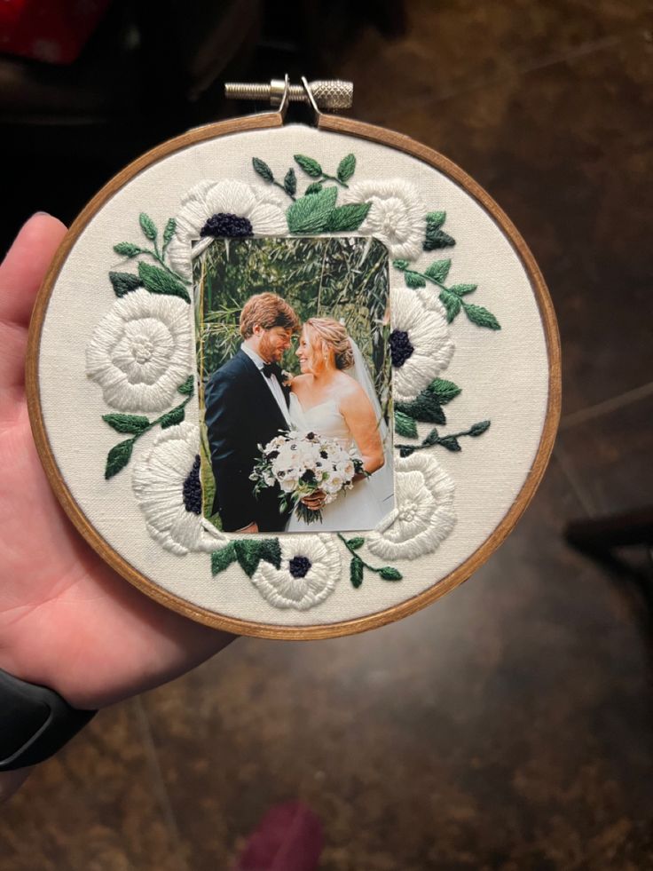 a hand holding a white embroidered photo frame