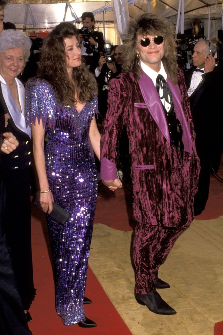 two people in purple outfits walking on a red carpet