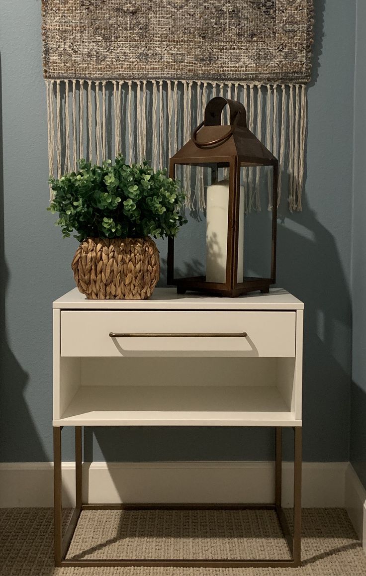 a white table topped with a potted plant next to a lamp