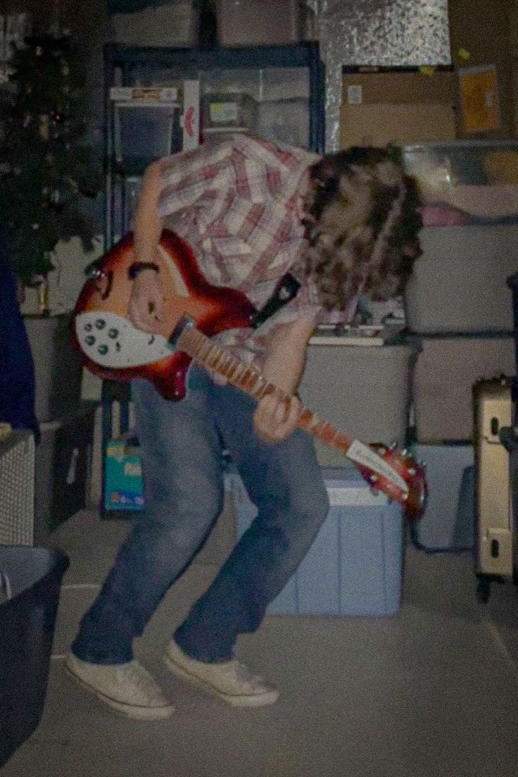 a man playing an electric guitar in a room