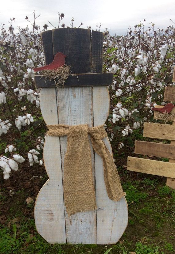 a snowman made out of wood and burlock with a bird on top