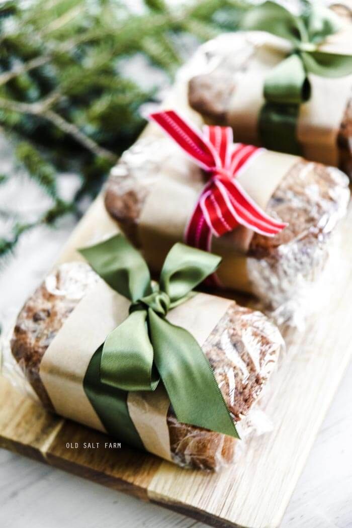 three rolls wrapped in brown paper and tied with green ribbon sitting on a cutting board