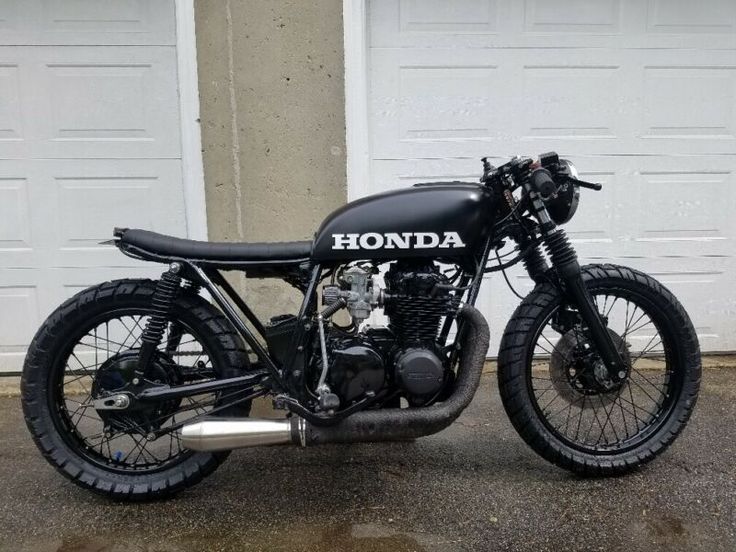 a black motorcycle parked in front of two garage doors with the words honda on it