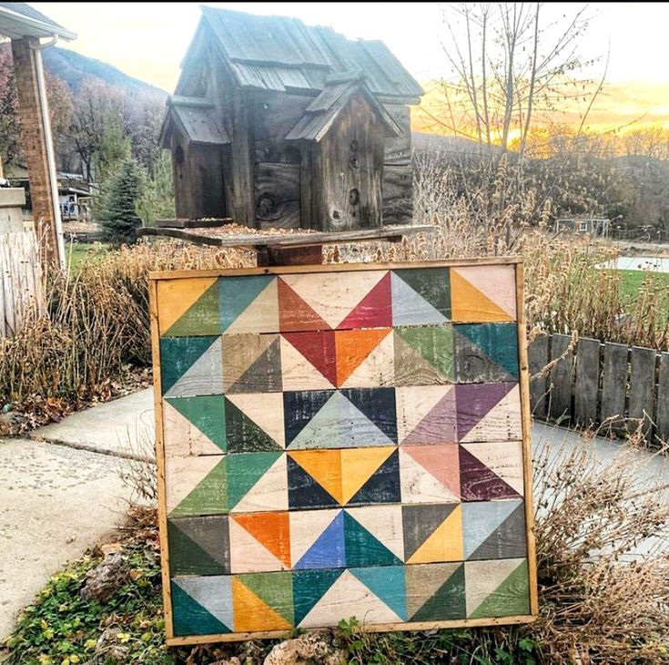 an old wooden sign sitting on the side of a road next to a building with a barn in the background