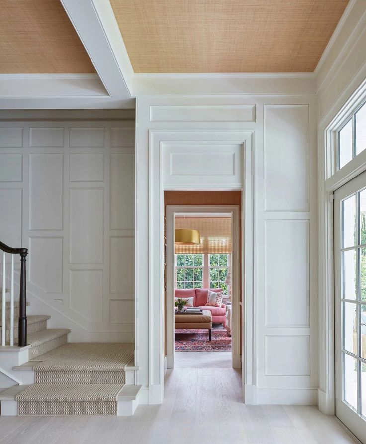 an open door leading to a living room with white walls and wood flooring on the stairs