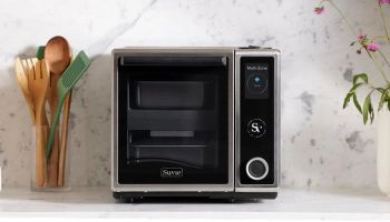 a microwave oven sitting on top of a counter next to utensils and flowers