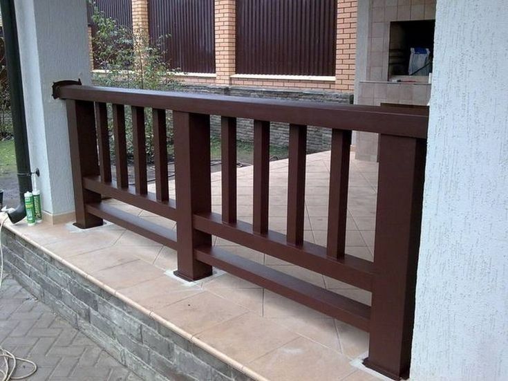 a brown wooden balcony railing next to a brick building